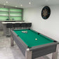 games room in a green theme with a pool table and darts board and bar with dark grey stools