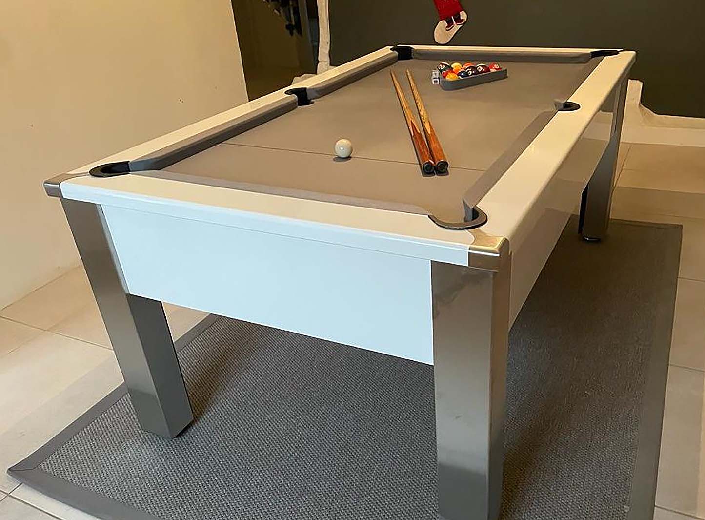 gloss white framed pool table with light grey cloth cues and balls