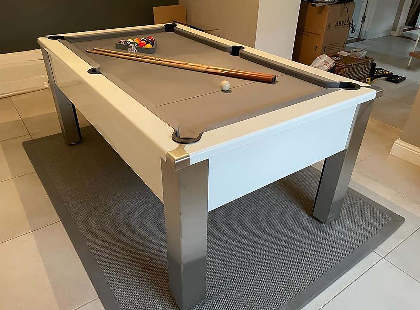 gloss white framed pool table with light grey cloth cues and balls