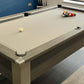 close view of a light grey cloth pool table with spots and stripes balls cued up