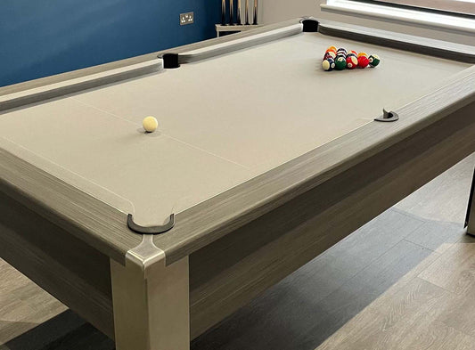 close view of a light grey cloth pool table with spots and stripes balls cued up