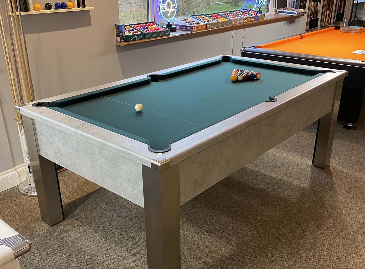 a pool table with dark green cloth spots and stripes balls and light grey body